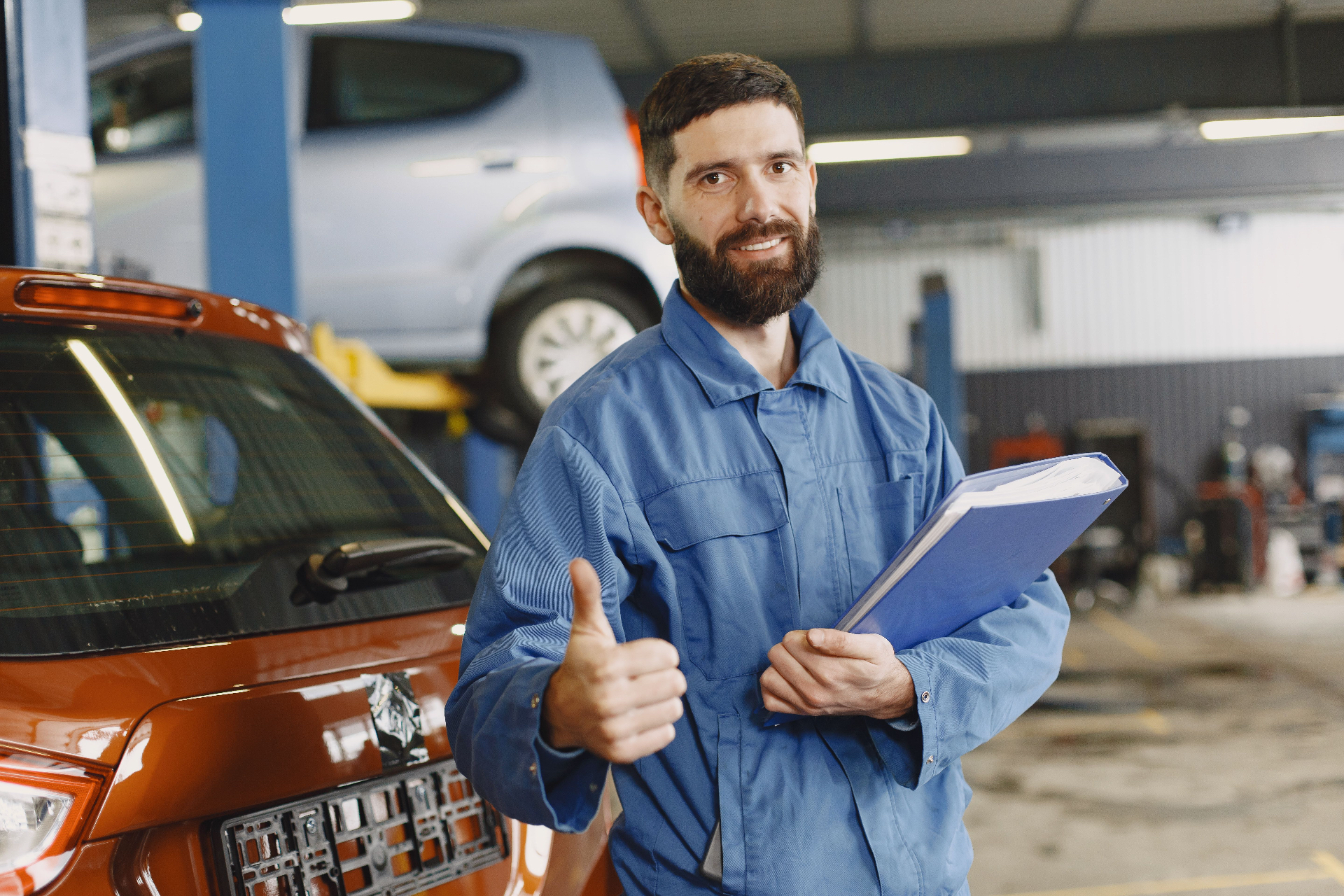Vetted mechanic partner giving a thumbs up next to a car in the workshop